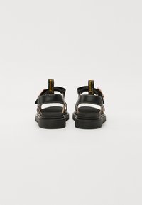 Sorte sandaler med justerbare stropper, en robust gummisåle og kontrasterende gule og rosa detaljer. Åpen bakdesign for pusteevne.
