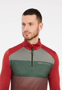 Rode en groene sportieve zip-up shirt met lange mouwen en een geruit patroon op de borst, en een logo aan de linkerkant. Gladde textuur.