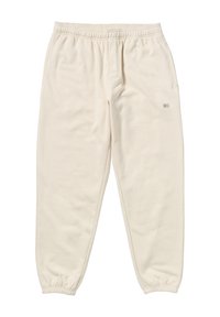 Cremefarbene Sweatpants aus weichem Stoff, mit elastischem Bund, schmalen Knöcheln und einem kleinen Logo-Tag auf der Vorderseite.