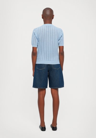 Light blue ribbed knit short-sleeve top with a fitted design, paired with dark denim shorts, featuring a relaxed fit and visible back pockets.