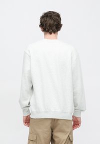 Graues Fleecepullover mit Rundhalsausschnitt, überschnittenen Schultern und gerippten Bündchen. Schlichtes Design, weiche Textur und lockere Passform.