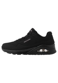 Black athletic shoes featuring a smooth synthetic upper, lace-up design, air-cushioned sole, and perforated details for breathability.