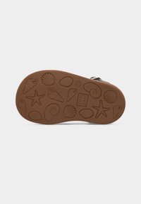 Καφέ σόλα παπουτσιού με ανάγλυφα σχέδια από θαλασσινά κοχύλια, αστερίες και σπειροειδή κοχύλια, συμπεριλαμβανομένου του ονόματος της μάρκας "POM D'API" και του μεγέθους "20".