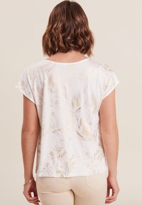 Witte top met korte mouwen, versierd met een goudkleurig loofpatroon, van zacht materiaal, met een losse fit en een ronde halslijn.