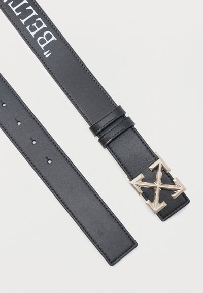 Μαύρη δερμάτινη ζώνη με ασημένια πόρπη σε σχήμα βέλους και λευκή επιγραφή "BELT" που φαίνεται μερικώς στην εσωτερική πλευρά του ιμάντα.