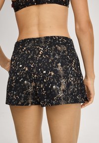 Černé šortky s texturovaným vzorem leopardí a hadí potisk v béžové a bílé barvě. Elastický pas s bočními rozparky pro lepší pohyb.