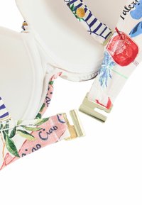 Close-up of white padded bra with colorful floral and striped fabric straps and gold metal clasp unhooked.