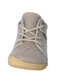 Zapato de piel beige con puntera redonda, acentos cosidos y cordones beige. Presenta detalles perforados a los lados y una suela de goma flexible.