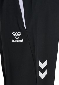 Zwarte sportbroek met wit logo en chevronpatroon aan de zijkant, gemaakt van een soepele en lichtgewicht stof.