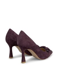 Chaussures à talons hauts en suède violet avec un design à bout ouvert, dotées d'un détail de nœud décoratif et d'un talon fin. Texture lisse, bout pointu.