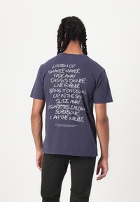 Navy blue cotton t-shirt featuring white text on the back with song titles. Short sleeves, round neck, relaxed fit, and straight hem.