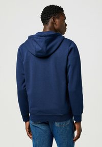 Felpa blu navy realizzata in misto cotone, con cappuccio, polsini a costine e orlo dritto. Il retro presenta una superficie liscia senza pattern.