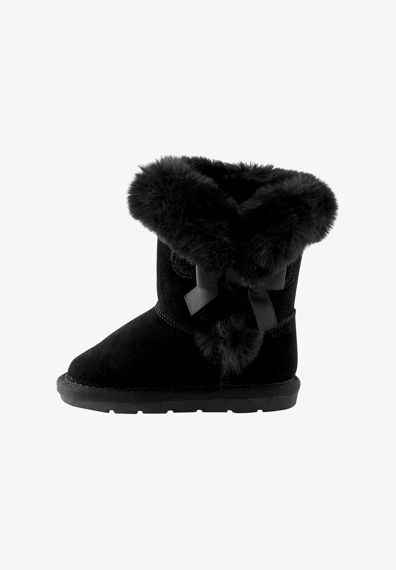 Bottine noire en suède avec une bordure en fausse fourrure et un détail en noeud sur le côté. Semelle en caoutchouc plate, design à bout rond, texture chaude.