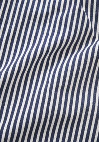 Gros plan sur un tissu rayé vertical bleu marine et blanc avec de légers plis, montrant la texture et le motif.