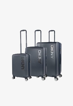 Tres maletas rígidas DKNY en gris oscuro, con superficie texturizada, ruedas suaves y asas retráctiles.