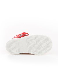 Zapatilla roja con parte superior de lona estampada, suela exterior de goma blanca y detalles de hilo cerca del talón, marcadas "HECHO EN ESPAÑA" en la suela.