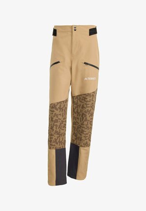 Beige sportieve broek met een patroon in bruine onderste panelen, zwarte accenten en ritszakken. Voorzien van een drukknoopsluiting en een verstelbare tailleband.