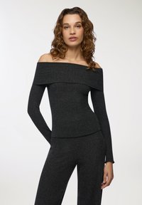 Top typu off-shoulder, prążkowany w ciemnoszarym kolorze z długimi rękawami, z szerokim dekoltem i dopasowanym krojem. Miękka tekstura, minimalne detale.