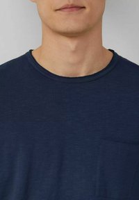 Himmelblaues Kurzarm-T-Shirt mit Rundhalsausschnitt und Brusttasche. Weiche Textur mit glatter Oberfläche, minimales Design.