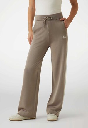 Beige wide-leg sweatpants with a drawstring waist, side pockets, and embroidered logo on the front. Made of soft, smooth fabric.