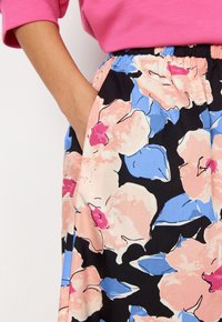 Floraler Midirock in Schwarz mit großen pinken, blauen und lila Blumenmustern. Verfügt über einen elastischen Bund und Seitentaschen. Weicher Stoff.