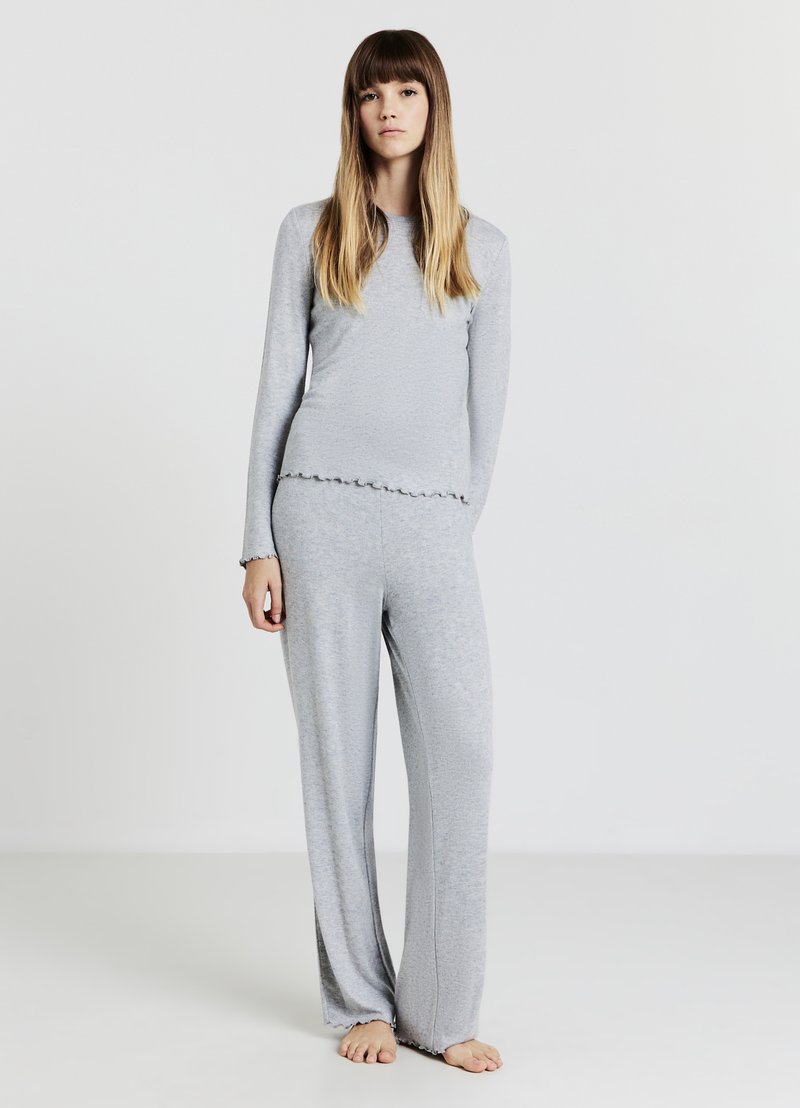 Haut gris à manches longues et pantalon assorti en tissu doux, avec un ourlet festonné et une coupe décontractée. La tenue présente une texture lisse.
