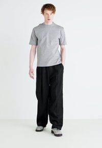 Gray short-sleeve t-shirt paired with loose black trousers. The outfit features a relaxed fit and a simple design, suitable for casual wear.