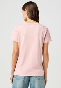 T-shirt rosa di cotone a maniche corte con scollo rotondo. Tessuto liscio, vestibilità standard e retro semplice senza motivi o grafiche.