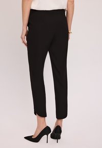 Czarne dopasowane spodnie o wąskim kroju, do kostek, z subtelnymi bocznymi rozporkami. Połączone z czarnymi szpilkami.