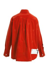 Camisa de algodón rojo con cuello, patrones circulares bordados y un detalle de etiqueta blanca en el costado. Presenta puños abotonados y un corte relajado.