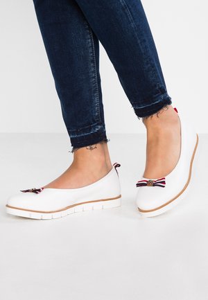 Ballerines blanches à bout rond, dotées d'un accent en forme de nœud rayé et d'une semelle blanche flexible avec une légère bordure marron.