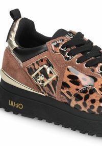 Sneakers med leopardprint, der har en blanding af ruskind og patentmaterialer, sorte snørebånd, metalliske accenter og en tyk gummisål.