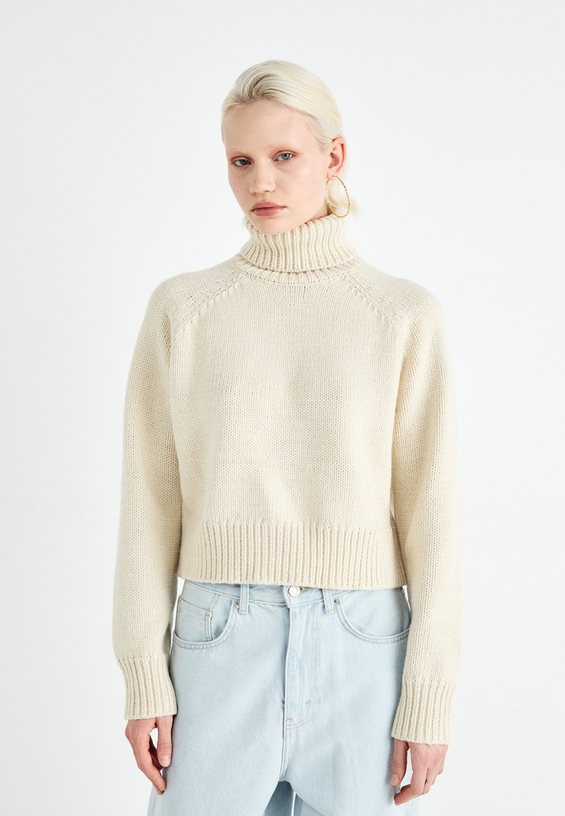 Beige, ribbed, knitted turtleneck sweater with a cropped design and long sleeves, featuring a textured pattern and relaxed fit.