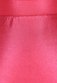 Tessuto lucido e liscio di un vivace rosa con una leggera lucentezza, che presenta una parte arricciata in vita.