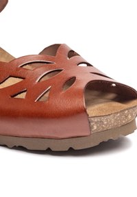 Sandalo in pelle marrone con design a fori, superficie testurizzata, soletta in sughero e suola in gomma. Stile aperto davanti, con punta curva.