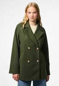 Olijfgroene dubbele-breasted jas van zacht materiaal met gouden knopen, grote revers en zijzakken.