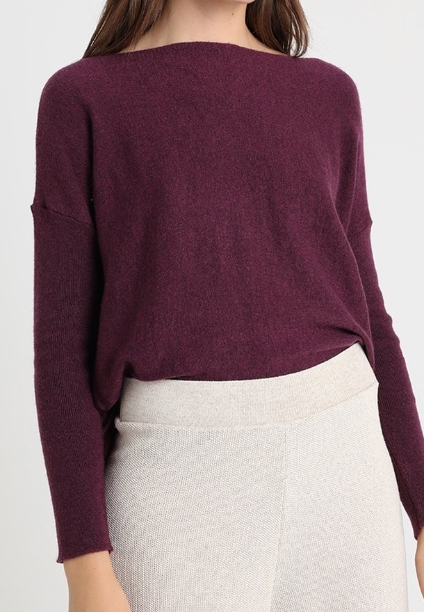 Pull en tricot bordeaux avec une coupe décontractée, un col bateau et des manches longues, associé à un pantalon texturé beige taille haute.