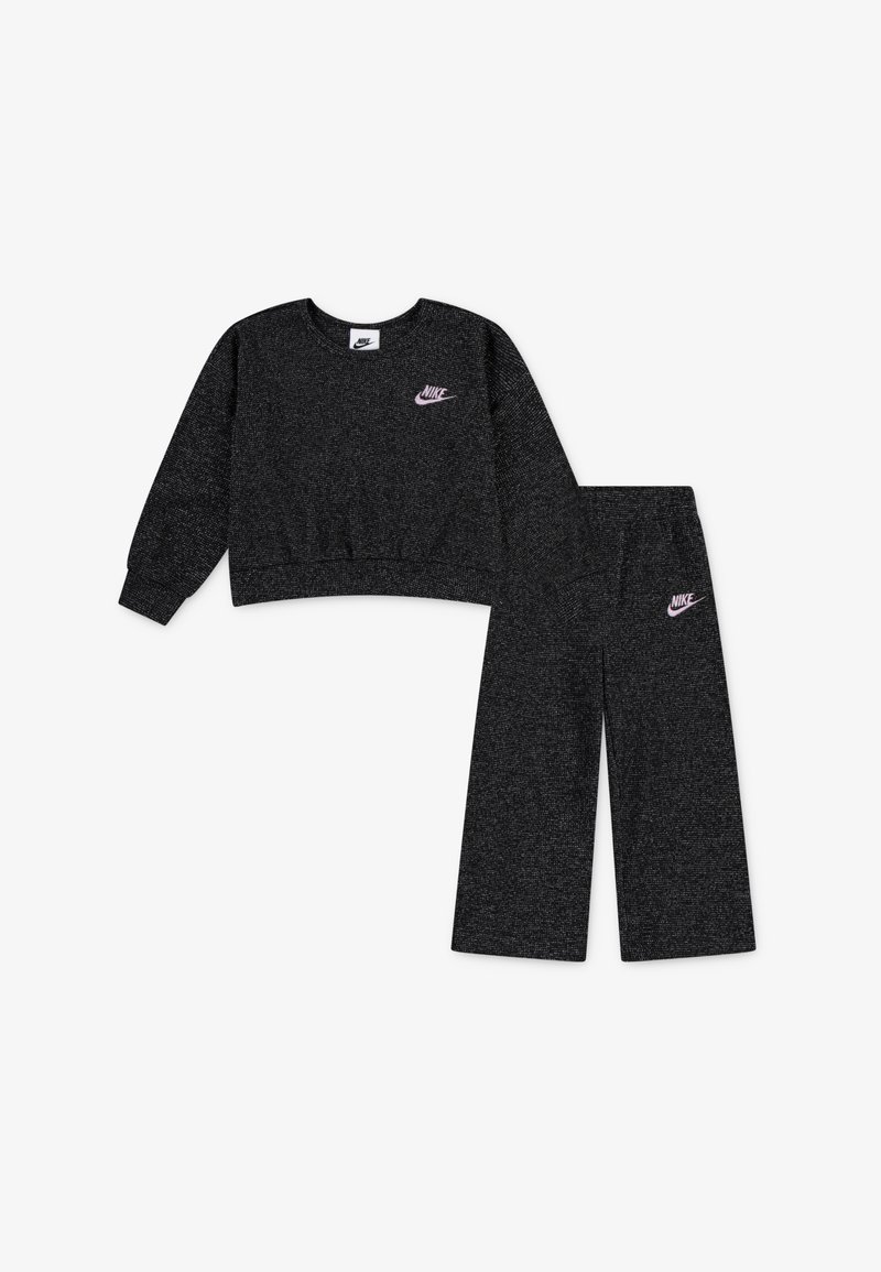 Čierna mikina a zodpovedajúce široké nohavice vyrobené z textúrovanej látky, s malým ružovým logom Nike na hrudi a nohaviciach.