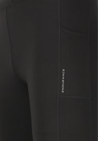 Schwarze Sportleggings mit glatter Textur, ausgestattet mit einer Seitentasche und einem reflektierenden "ENDURANCE"-Logo an der äußeren Oberschenkelseite.