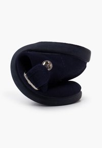 Zapato azul marino tipo slip-on con forma flexible y curvada y suela de goma. Cuenta con material de lona y un detalle de botón metálico.