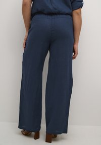Mornarsko modre široke hlače iz lahkega materiala, ki imajo sproščen kroj in elastičen pas za udobje.