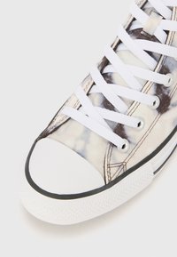 High-top sneaker with a patterned fabric upper in cream and grey, white laces, rubber toe cap, and black trim along the sole.