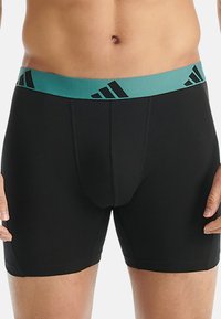 Czarne bokserki z turkusowym pasem w talii ozdobionym czarnymi ukośnymi paskami. Wykonane z gładkiego, elastycznego materiału zapewniającego wygodę.