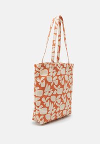 Sac cabas orange et blanc avec motif floral abstrait, forme rectangulaire et deux longues anses pour porter à l'épaule.