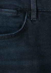 Tissu en denim bleu foncé en gros plan montrant une poche avant, une boucle de ceinture et des coutures visibles sur un jean.