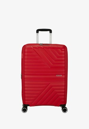 Punainen kovakuorinen matkalaukku, jossa on kuvioidut vinoviivat, neljä pyörää, teleskooppikahva ja etuosassa American Tourister -logo.