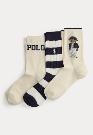 Drie paar crew sokken in crème en marineblauw; één met "POLO" tekst, één gestreept met een paardenlogo en één met een beer gekleed in marineblauw en wit.