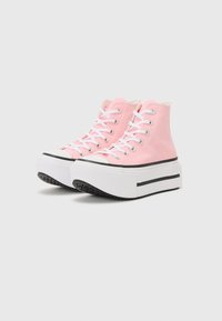 Pink high-top platform sneakers with white laces, rubber soles, and black accents. Canvas material and textured surface.
