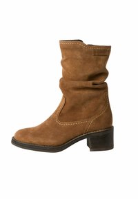Bottine en suède marron avec un design froncé, un bout arrondi, des coutures décoratives et un petit talon carré. Fermeture éclair sur le côté.