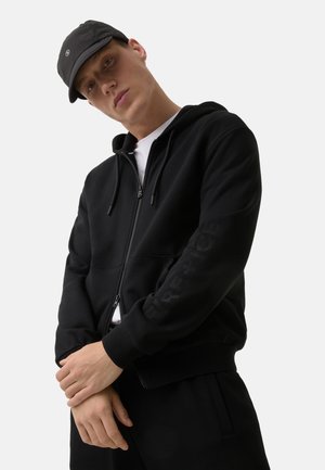 Sort zip-up hoodie med en afslappet pasform, med et tekstureret "FIRE + ICE" logo på ærmet og ribbet kant og manchetter.